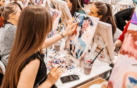 A young woman painting on a canvas.